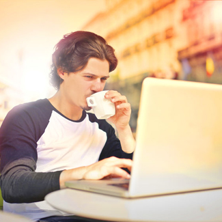 Mann mit Kaffeetasse und Laptop